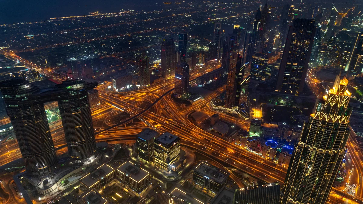 Aerial night view of a city skyline with glowing highways and skyscrapers