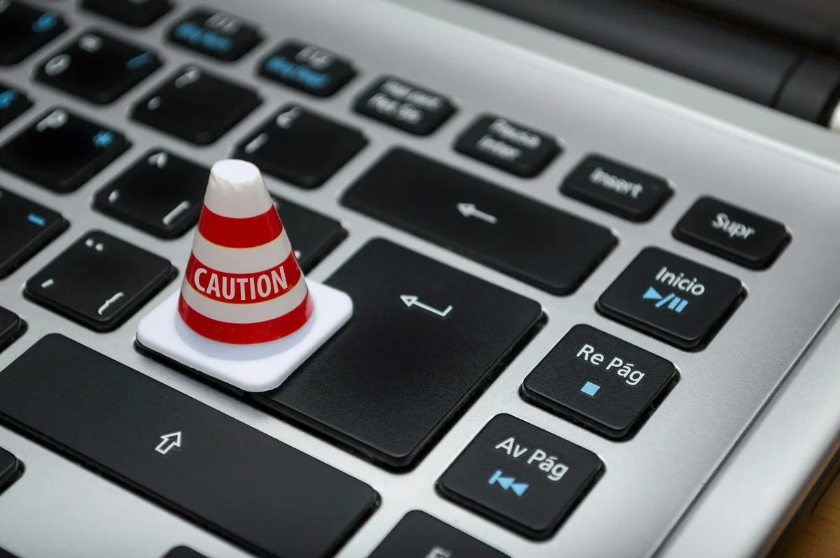 Miniature striped caution cone sitting on a laptop keyboard
