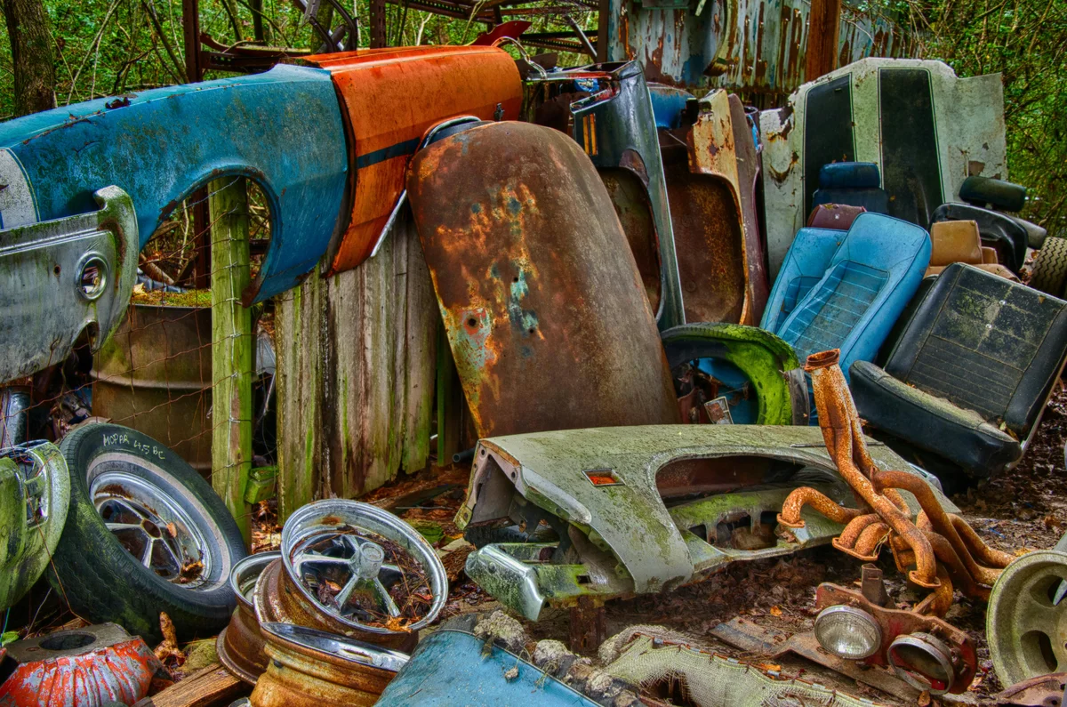 Junkyard pile of rusted car bodies, fenders, hubcaps, and old parts