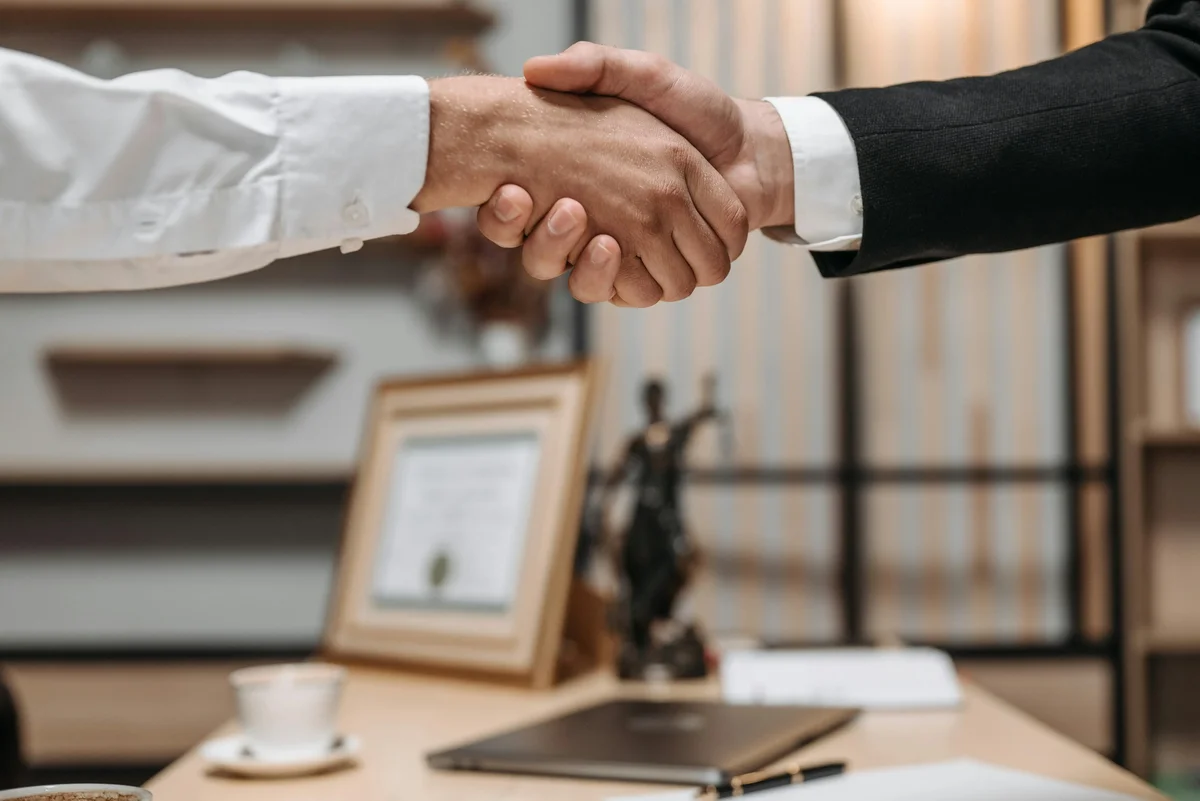 Close-up of two people shaking hands over an office desk