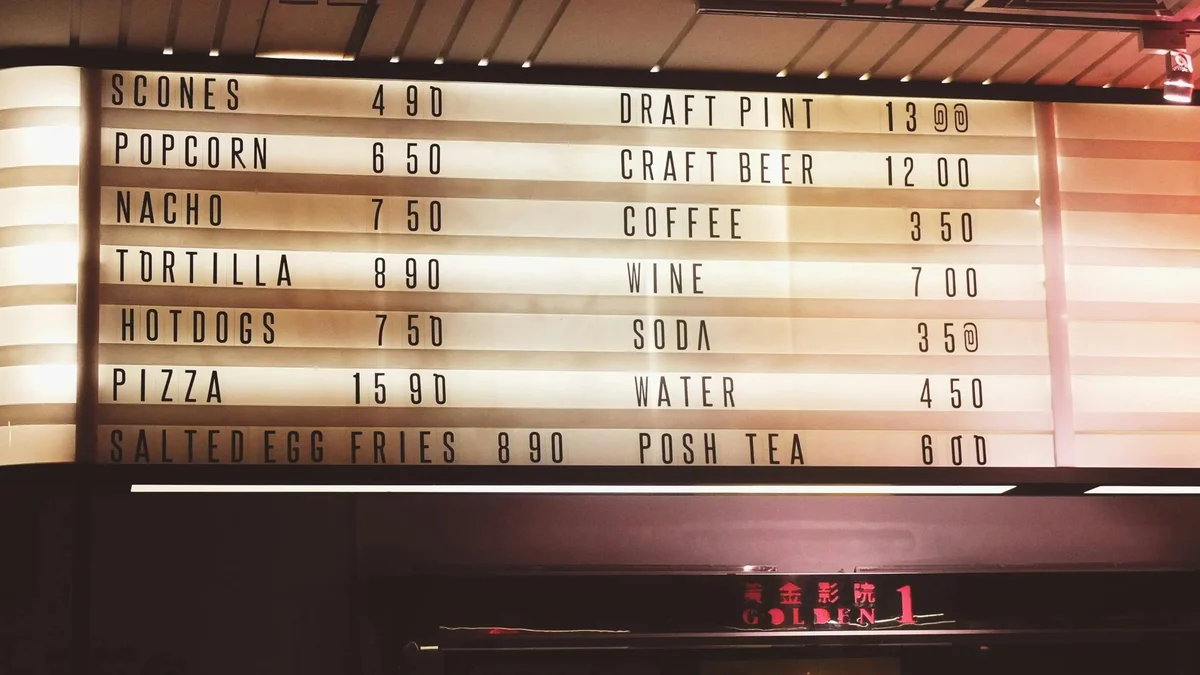 Backlit cinema menu board listing snacks and drinks with prices