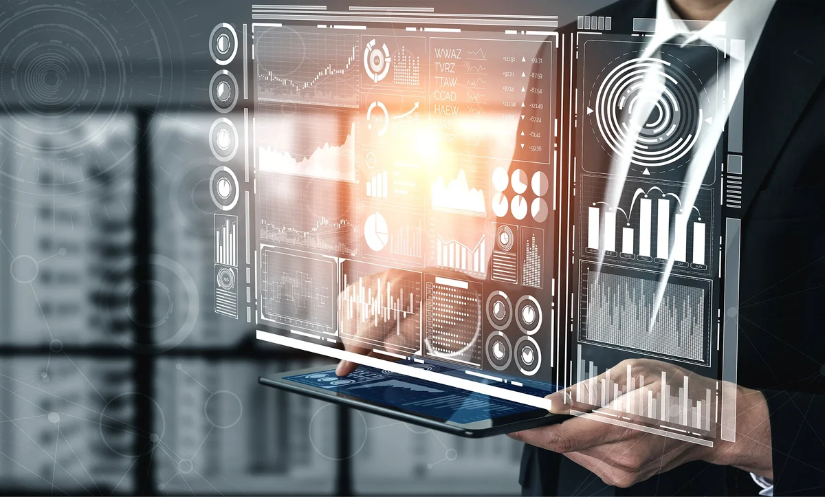 Person in a suit holding a tablet projecting a holographic data dashboard