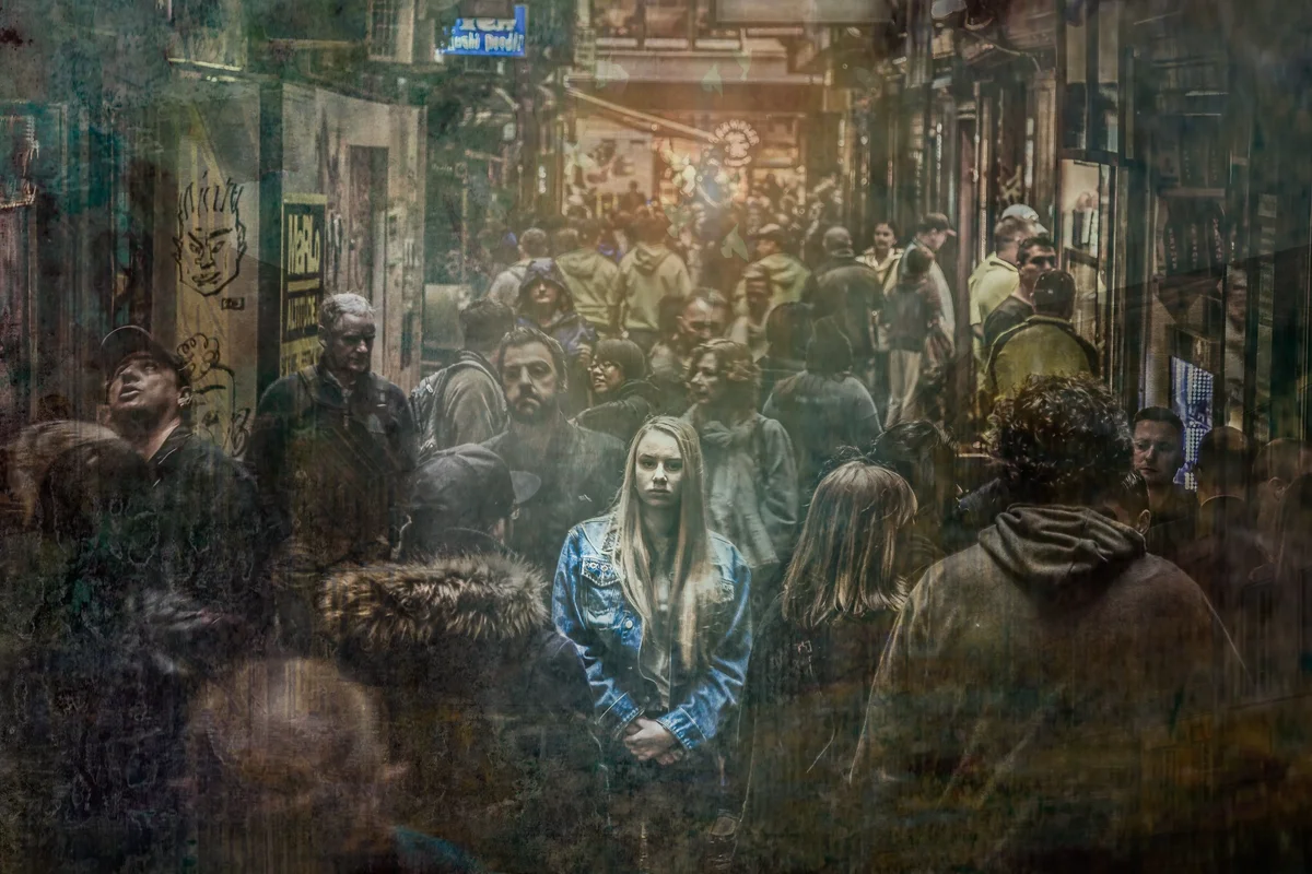Woman standing still amid a blurred crowd in a busy city alley
